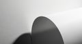 A rolled sheet of white paper casts a shadow on a white, textured surface. The paper Royalty Free Stock Photo