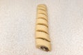 Rolled and sliced yeast dough with stuffed fried mushrooms, raw patty before baking, lying on the table.