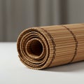 A rolled-up bamboo mat sits on a white surface. The mat consists of narrow, parallel Royalty Free Stock Photo