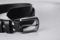 Rolled up black leather belt with buckle and rivets on a gray background Royalty Free Stock Photo