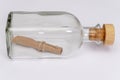 A rolled-up old paper note in a glass bottle with a cork on a light background. Concept: sea mail, a message from an island, a req Royalty Free Stock Photo