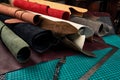 Rolled up samples of textures of genuine leather of different colors on a leather background, on a table with mats and Royalty Free Stock Photo