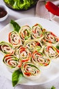 Rolled up sandwiches with lettuce, bacon and baked peppers in a tortilla on a plate vertical view Royalty Free Stock Photo
