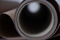A rolled-up sheet of thick paper, viewed from the side, showing the inner core with a gradient light reflection inside.
