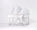 Rolled white soft terry towels in the basket against a white backdrop. Striped towels in a white basket in front of a white