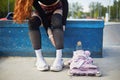 Young skater girl putting on protective shin guards and knee pads for skating. Unrecognizable female roller blader preparing for a