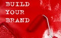 Roller brush with red paint with text BUILD YOUR BRAND , business concept