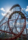 Roller coaster with red tracks and an inversion loop set against a bright blue sky, Royalty Free Stock Photo