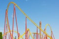 Roller coaster yellow-red up down turn and a passing loop feint, spiral train of trolleys tends to go down, tower with free fall Royalty Free Stock Photo