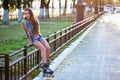 Roller girl wearing jeans sitting on iron fence