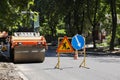 Roller near barricade with traffic signs on city street. Road repair Royalty Free Stock Photo