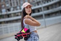 Pretty girl in cap carrying roller-skates in hands