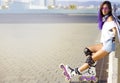 Roller skating young Caucasian girl with violet hair, sunglasses and protection outdoors sitting on parapet Royalty Free Stock Photo