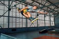 Rollerblader jump high from big air ramp performing trick. Indoors skate park equipment. Royalty Free Stock Photo
