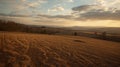 Rolling brown agricultural field slopes gently downward into a distant valley during a tranquil sunset with soft clouds scattered Royalty Free Stock Photo
