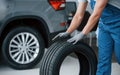 Rolling it on the floor. Mechanic holding a tire at the repair garage. Replacement of winter and summer tires Royalty Free Stock Photo