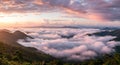 Rolling hills covered with lush greenery rise through a sea of white clouds, creating a Royalty Free Stock Photo