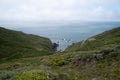 Rolling hills and hiking path lead down into a rocky cove in the ocean