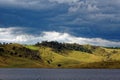 Softly undulating hills and patchy clouds at lake in Australian nature park Royalty Free Stock Photo