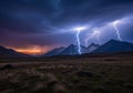 Rolling hills and mountains under a dramatic sky lit by multiple lightning strikes. The foreground Royalty Free Stock Photo