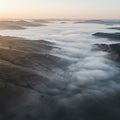 Rolling hills partially covered by a thick layer of low-lying clouds create a surreal