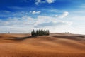 Rolling hills, small cypress trees forest and blue sky with clouds in tuscan landscape countryside panoramic view in an autumn day Royalty Free Stock Photo