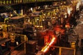 Rolling hot steel bars in steelworks finishing mill.