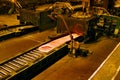 Rolling hot steel bars in steelworks finishing mill.