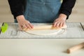 Rolling out the dough with a wooden rolling pin on a silicone baking mat. View of hands and workspace. copy space