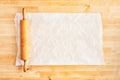 Rolling pin and crumpled piece of white parchment or baking paper on wooden table Royalty Free Stock Photo