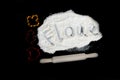 Rolling pin and inscription FLOUR on white flour and three cookie cutters on dark background flat lay. Free space for text