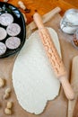 Rolling pin with a mustache pattern on a wooden decorated table covered with baked flour. Rolled dough with a pattern and cookie o