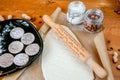 Rolling pin with a mustache pattern on a wooden decorated table covered with baked flour. Rolled dough with a pattern and cookie o