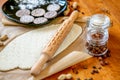 Rolling pin with a mustache pattern on a wooden decorated table covered with baked flour. Rolled dough with a pattern and cookie o