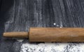 Rolling pin on textured black bord with traces Wheat Flour. Free space for text 