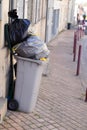 Rolling trash can overflowing bag grey wheelie in street city