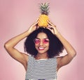 Rolling with the tropical times. Studio shot of a beautiful young woman posing with a pineapple on her head. Royalty Free Stock Photo