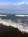 Rolling waves on beach with tall sail ship in distance Royalty Free Stock Photo