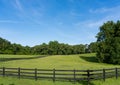 A rollling green field surrounded by trees and a wooden fence in a rural area in Georgia Royalty Free Stock Photo