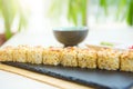 Rolls in a black plate on a wooden table. Fried sushi on black slate surface. Japanese food Royalty Free Stock Photo