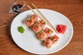 Rolls with chili pepper, red caviar, sesame, green onions, lie on a plate with wasabi, ginger and chopsticks