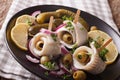 rolls of marinated herring with olives, onions, pickles and lemon close-up on a plate. Horizontal Royalty Free Stock Photo