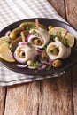rolls of marinated herring with olives, onions, pickles and lemon close-up on a plate. vertical Royalty Free Stock Photo