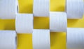 Rolls of new toilet paper lie on a yellow background