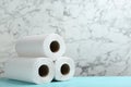 Rolls of paper towels on turquoise wooden table against marble wall, space for text Royalty Free Stock Photo