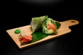 Rolls with salmon, salad leaf and cucumbers on a thick light wood stand with a ginger and wasabi Royalty Free Stock Photo