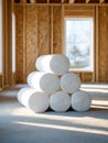 Rolls of white insulation material stacked inside an unfinished wooden frame building with sunlight streaming through large Royalty Free Stock Photo