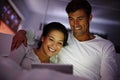 Rom coms are her favorite. a couple watching movies on a digital tablet while sitting in bed. Royalty Free Stock Photo