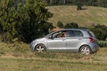 ROMA, ITALY - AUGUST 2018: Little adorable baby girl driving a silver car. Toyota Yaris and her mom are driving across the field