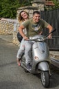 ROMA, ITALY - AUGUST 2018: Young happy couple in love riding a Vespa scooter along the way Royalty Free Stock Photo